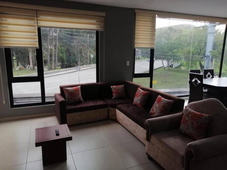 昆卡Departamento Acogedor: Nuevo y Amplio的带沙发、桌子和窗户的客厅