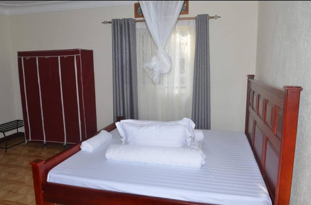 恩德培Migingo Suites的卧室内的一张带白色床单和枕头的床