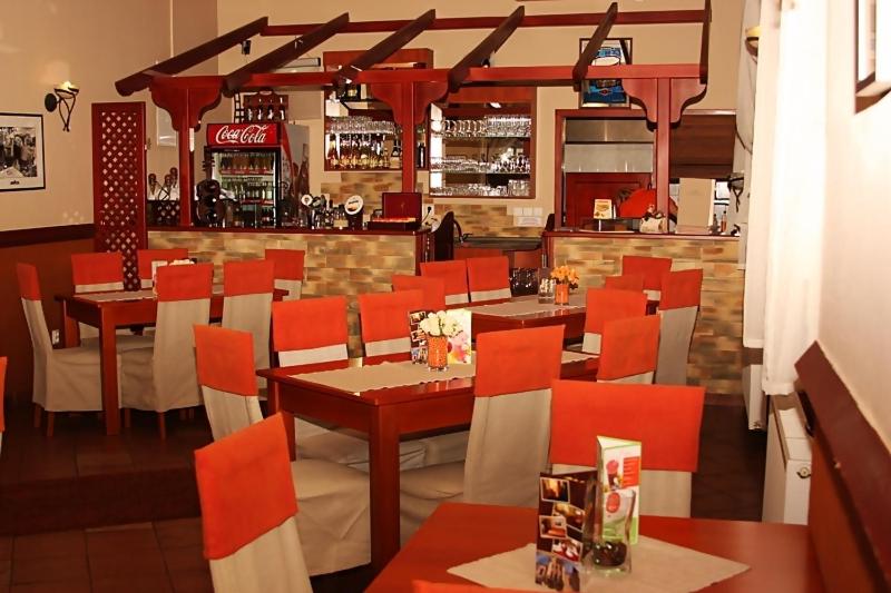 科马尔诺奥林普旅馆的一间设有红色桌椅的餐厅和一间酒吧
