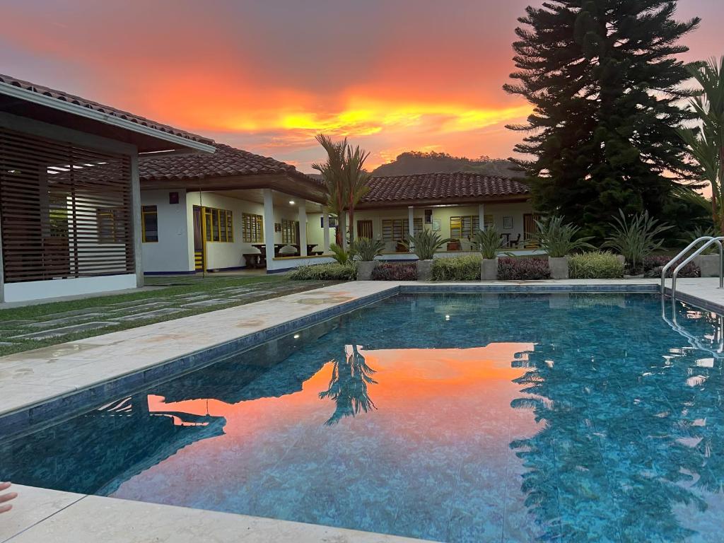 ChinchináThe Coffee Club Campestre的一座游泳池,位于一座享有日落美景的房屋前