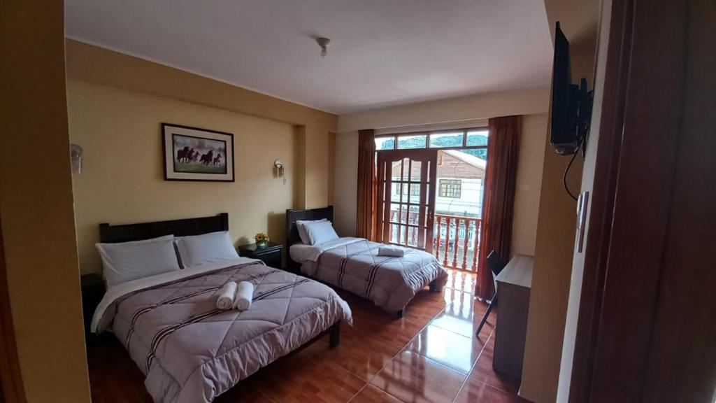 奥克萨潘帕Hospedaje "LOS QUETZALES DE OXAPAMPA"的酒店客房设有两张床和电视。