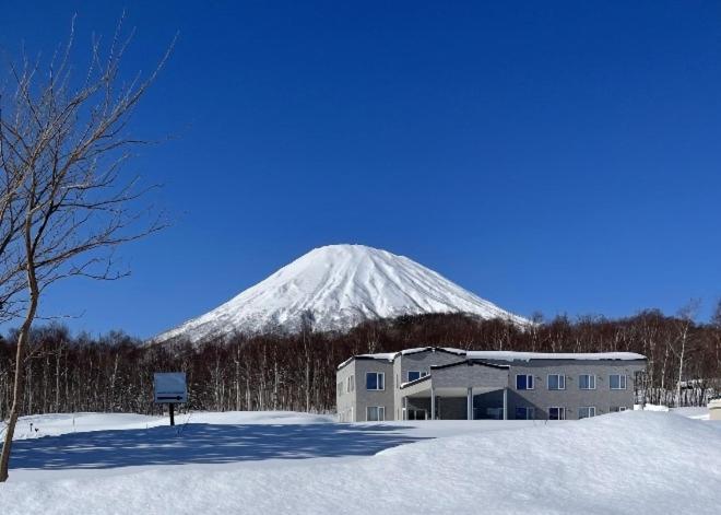Kyōgokuゲストハウス ikoi的一座建筑物前的一座大山后面的雪覆盖的山