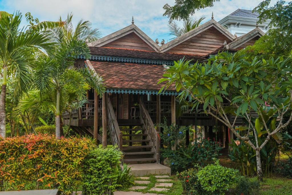 暹粒Phum Khmer Lodge - Village Cambodian Lodge的一座带楼梯和棕榈树的木屋