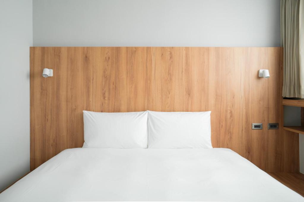 台东路得行旅台东2馆的一张带白色枕头和木制床头板的床