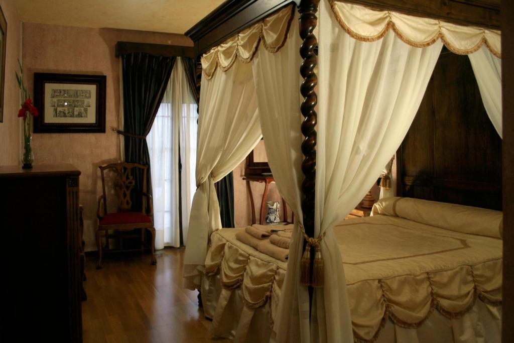阿拉尔孔La Posada del Hidalgo de Alarcón的一间卧室配有带窗帘的天蓬床