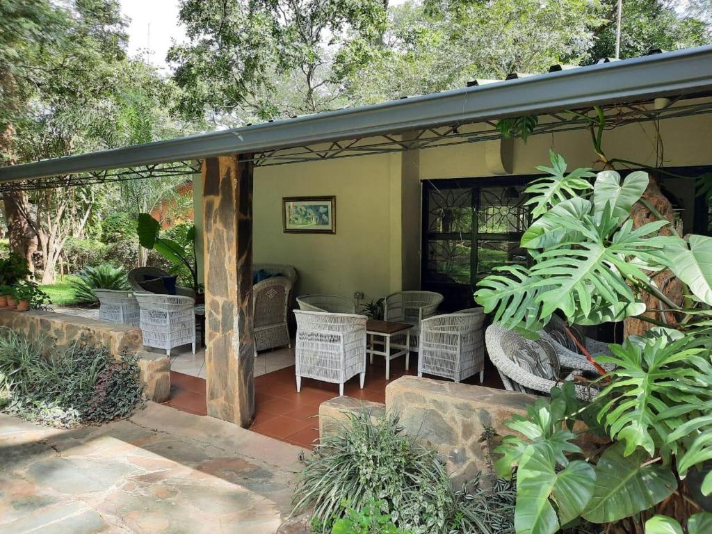 MkushiFika Lodge的一个带藤椅和桌子的有盖庭院