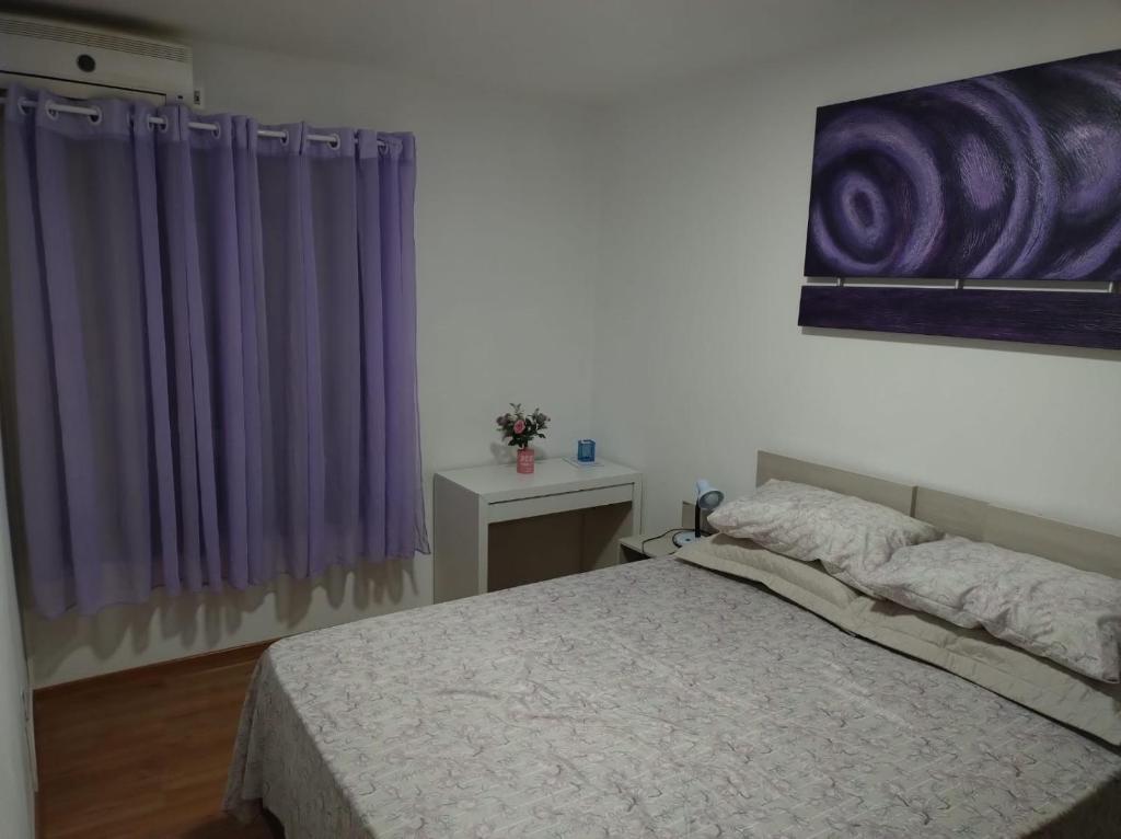 新彼得罗波利斯Apartamento Cantinho do Aconchego-Nova Petrópolis的一间卧室配有一张床和紫色窗帘