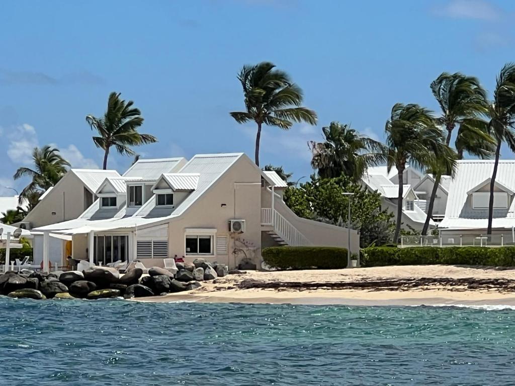 圣马丁岛Sweet Home SXM Baie Nettlé Pieds dans l'eau的棕榈树海滩上的白色房子