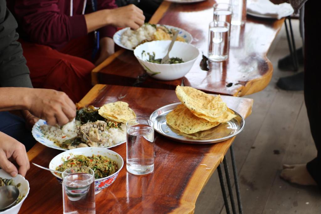 帕西加特Tsering's Homestay Oyan的一群坐在餐桌上的人,拿着盘子的食物