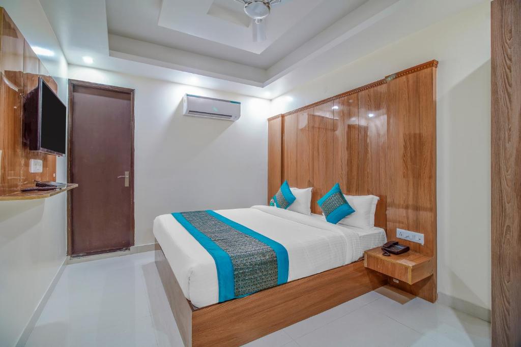 新德里hotel the paradise inn的一间卧室配有一张大床和木制床头板