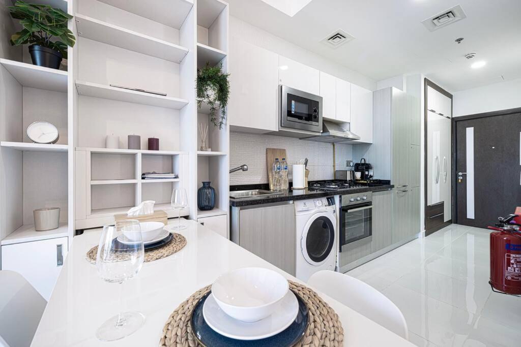 迪拜Dubai Sleek & Cozy Space的白色的厨房配有桌子和白色家电
