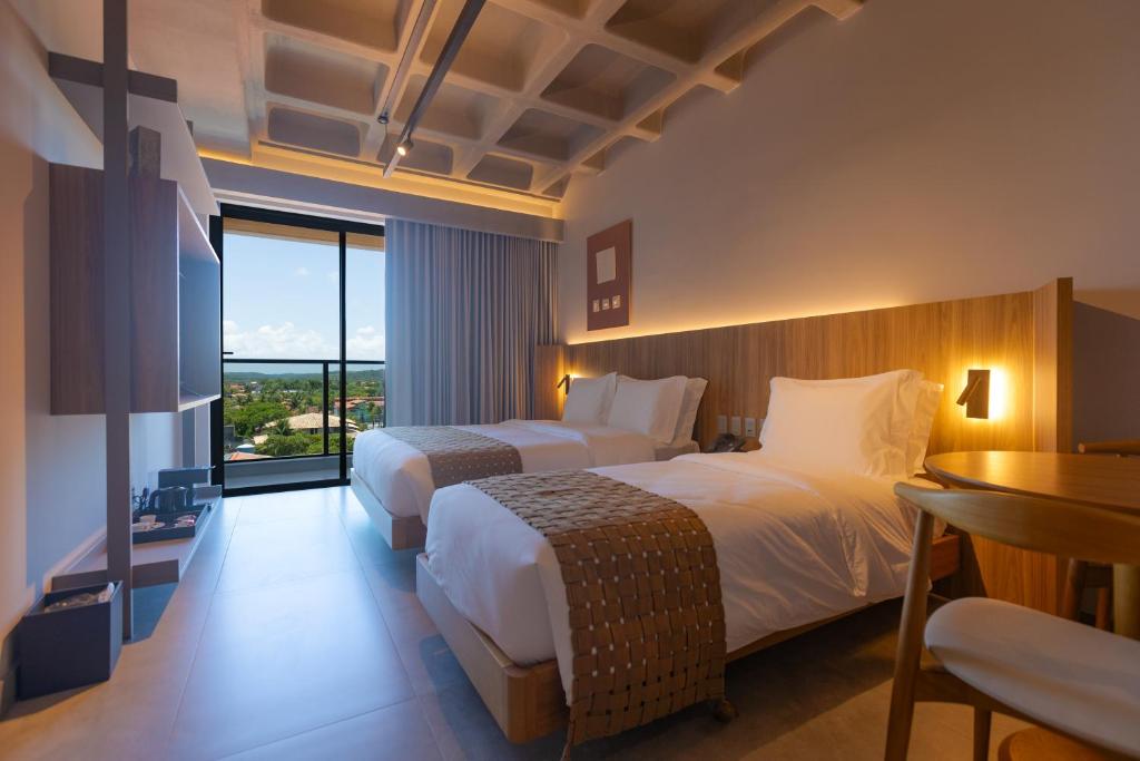 拉巴拉德纳圣米格尔Ritz Barra de São Miguel的酒店客房设有两张床和一张桌子。