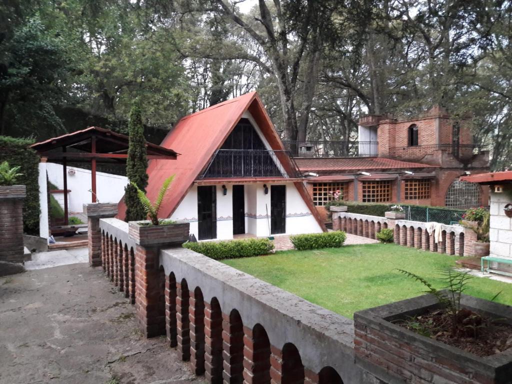 Santa Clara de JuárezCabaña de bosque con alberca的一座红色屋顶和围栏的房子