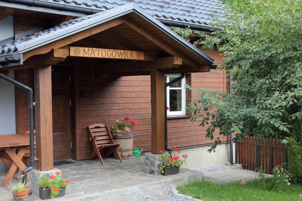 KrzeszowiceMATOGÓWKA的木结构建筑,带长凳和鲜花的门廊