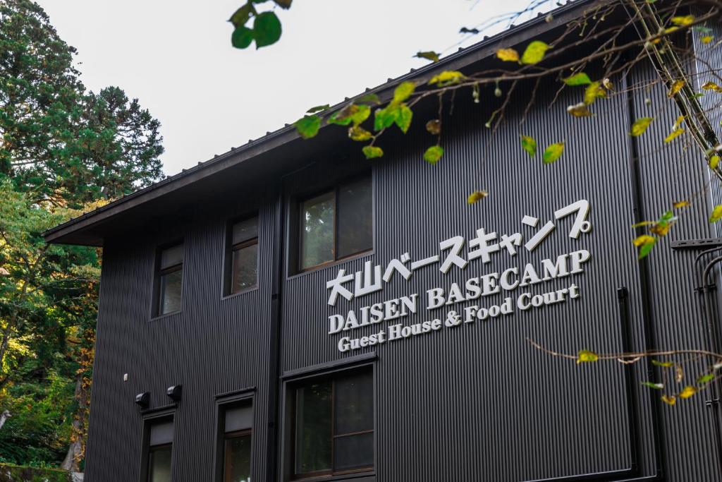 大山大山ベースキャンプ（Daisen Basecamp）的一座黑色的建筑,旁边有一个标志