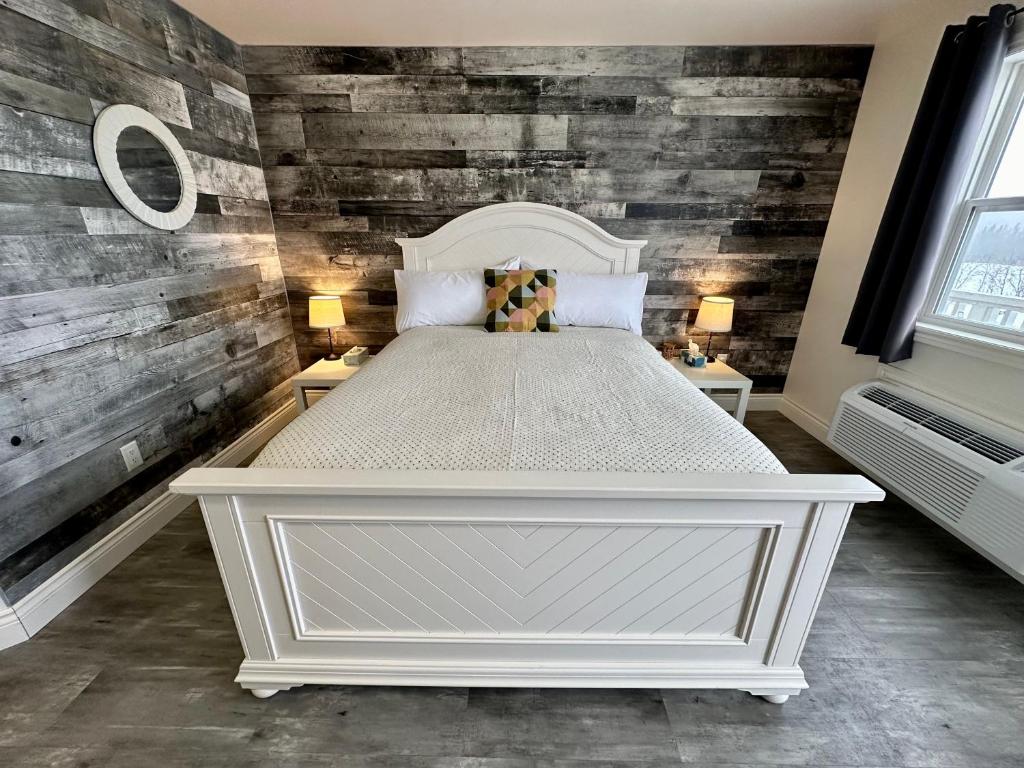 谢蒂坎普Cheticamp Outback Inn的卧室设有白色的床和木墙