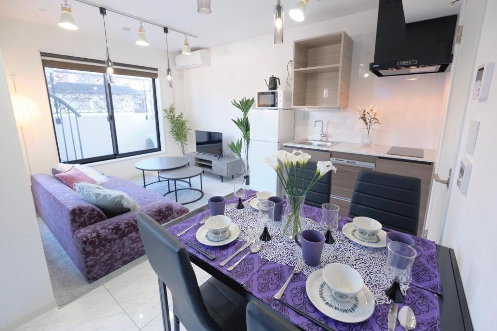 东京HJ PLACE TAKANAWA的厨房以及带紫色桌布桌子的客厅。