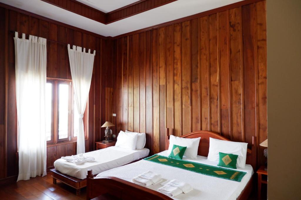 Muang KhôngKongmany Prestige Hotel的一间卧室设有两张床和木墙