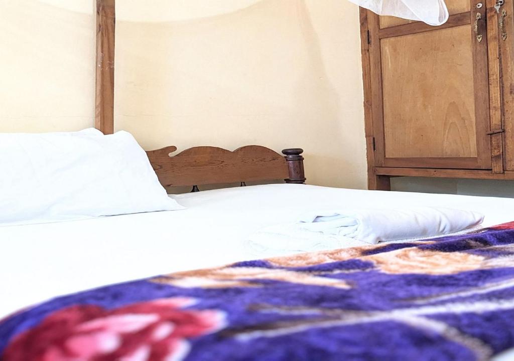 PanganiSea Hotel的一张带白色床单和彩色毯子的床