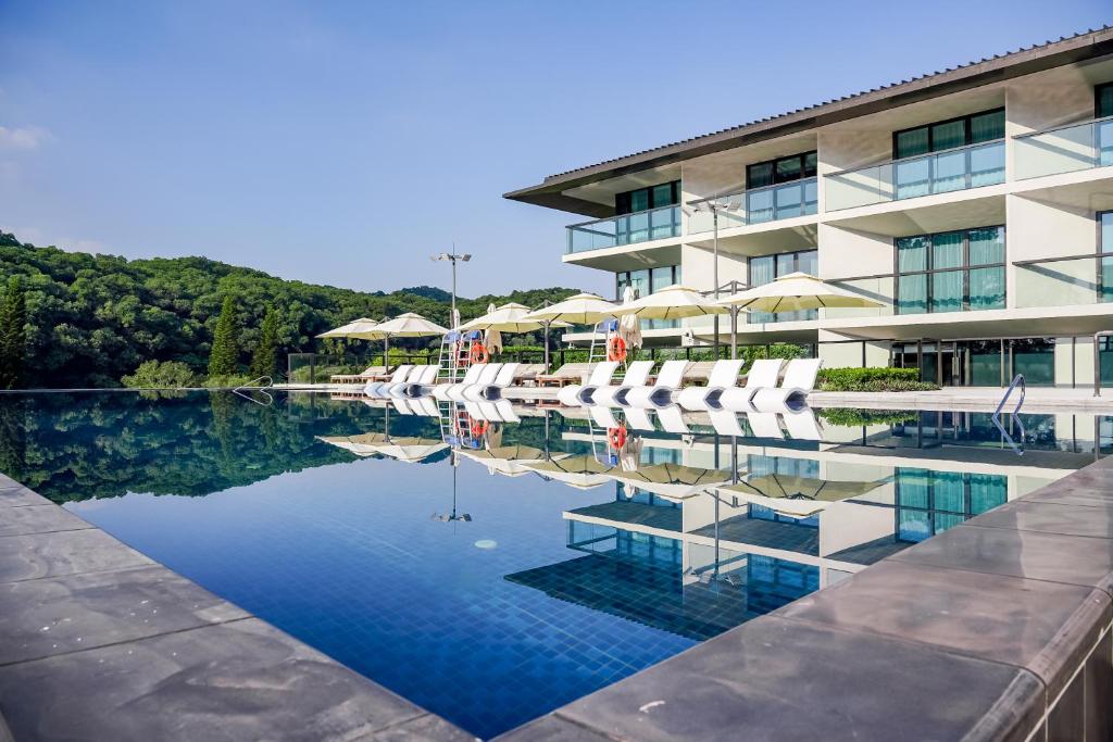 广州广州鸣泉居酒店的酒店设有带椅子和遮阳伞的游泳池