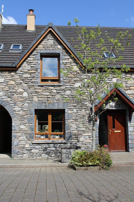 肯梅尔Cosy Holidayhomes Kerry的一座石头建筑,设有两扇窗户和一扇门
