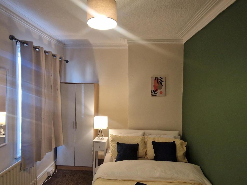 沃尔森德Executive 2-Bedroom House in Wallsend的一间卧室配有一张带绿色墙壁的床
