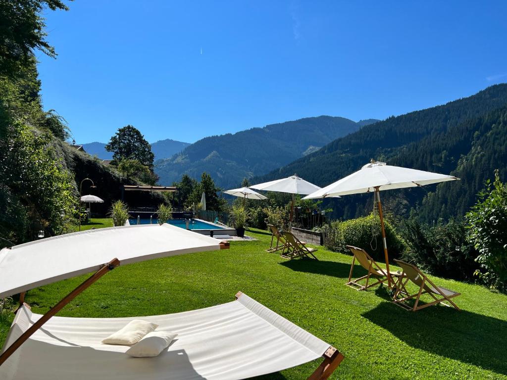 萨尔巴赫ALM SEASONS Premium Chalet & Studios的一个带椅子和遮阳伞的庭院和一个游泳池