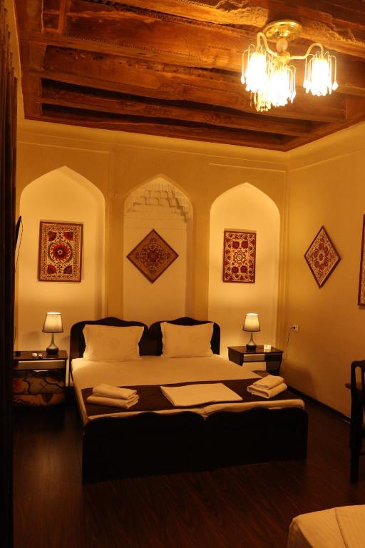 布哈拉Al Bukhari Boutique Hotel的一间卧室设有一张床、两盏灯和一个天花板。