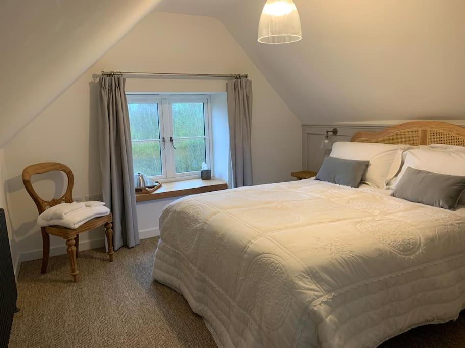 NorthleighStunning East Devon Cider Barn的一间卧室设有一张大床和一个窗户。