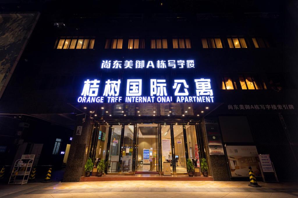 广州Orange Tree International Hotel Zhujiang New Town Huacheng Sqaure Branch - Free Shuttle Bus to Canton Fair Complex During Canton Fair Period的带有橙色火 ⁇ 标志的建筑