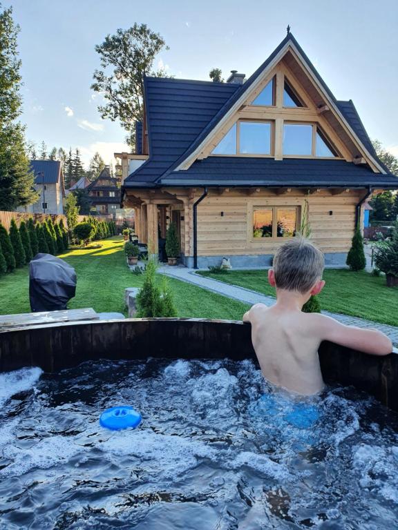 扎科帕内Nosalowski Wypas的坐在房子前热水浴池里的男孩