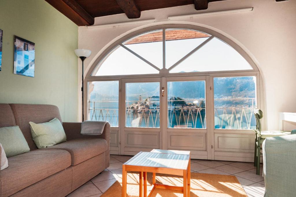 奥尔塔圣朱利奥-Ortaflats- Appartamento l'Isola的带沙发和大窗户的客厅