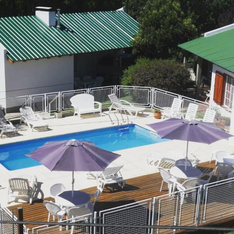 本塔纳山村Cabañas Aldea Serrana的游泳池旁设有椅子和遮阳伞