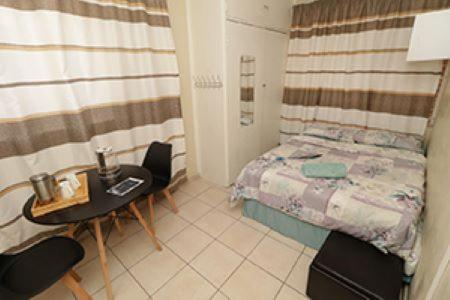 比勒陀利亚Las Palmas Day & Night Guest House的小房间设有一张床、一张桌子和椅子