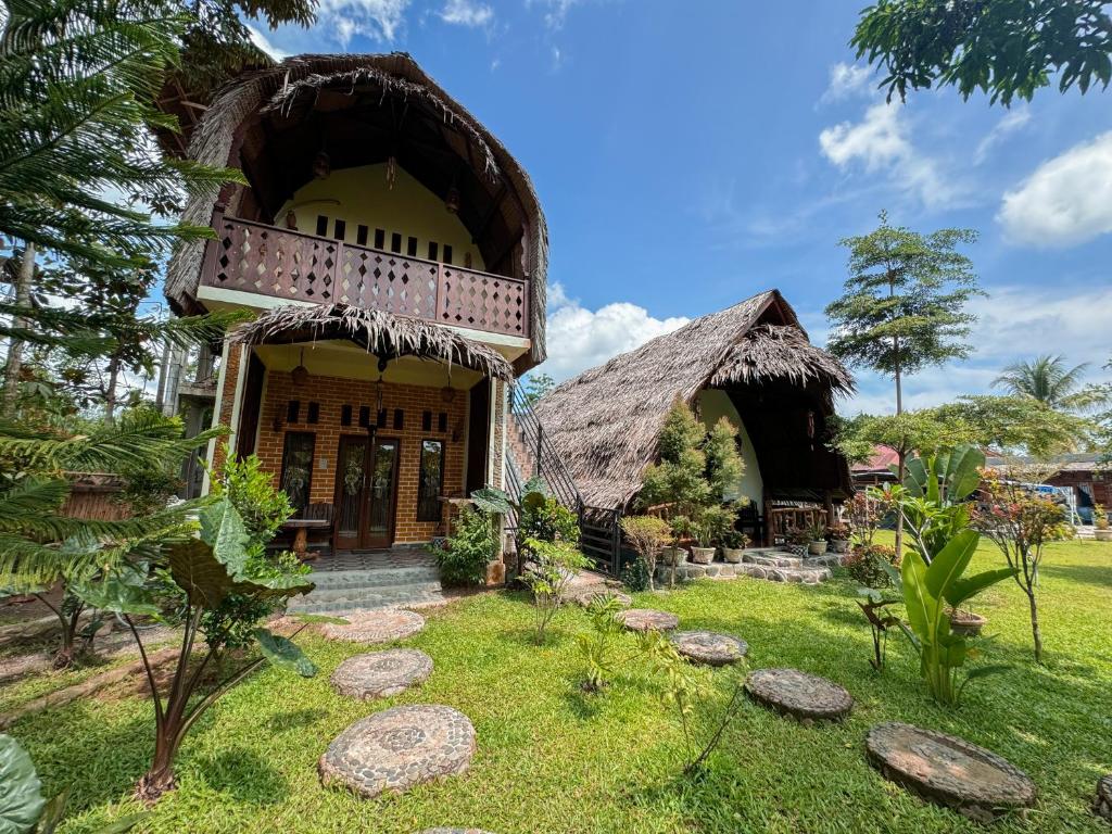 TimbanglawangSumatra Orangutan Treks Villa的茅草屋顶和庭院的房子
