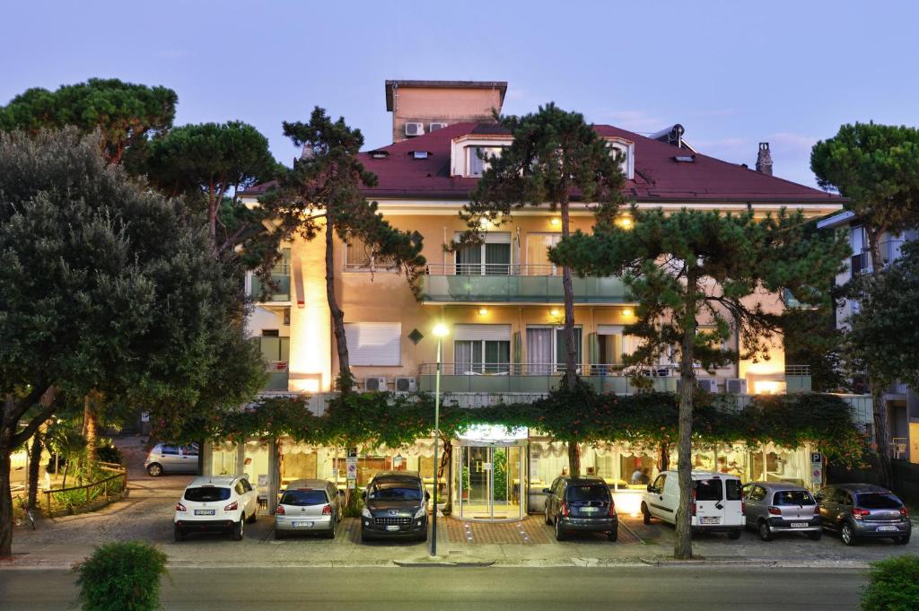 利尼亚诺萨比亚多罗Hotel Mimosa的停车场内停放汽车的大型建筑