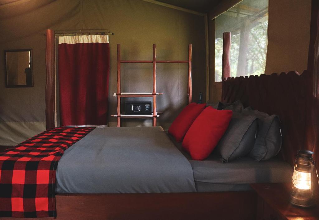 SekenaniDrunken Elephant Mara的一间卧室配有一张带红色枕头的大床