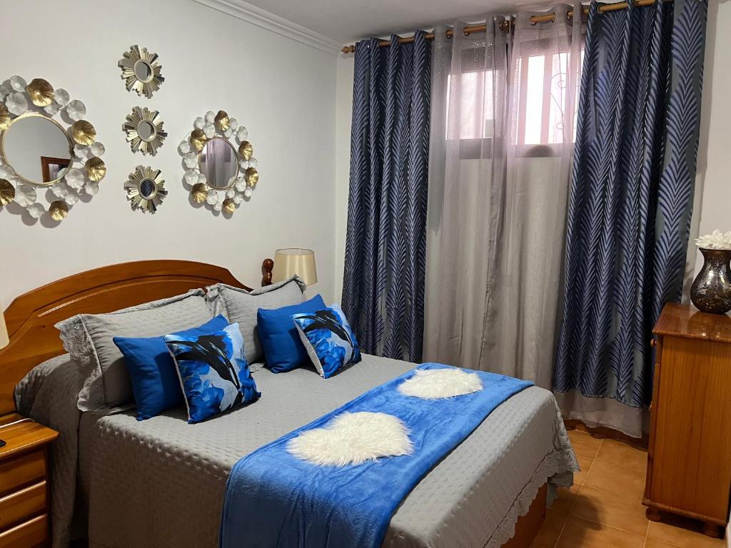 阿德耶La casita de la piscina的一间卧室配有一张带蓝色枕头的床和一扇窗户。