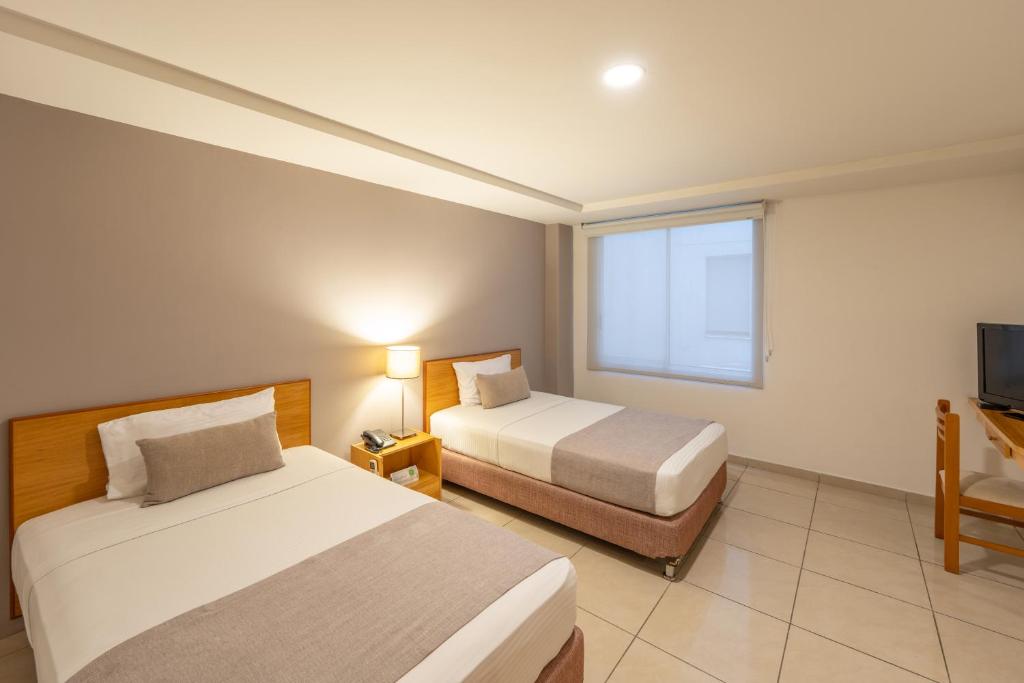 卡利Basic Hotel Centenario by Hoteles MS的酒店客房设有两张床和电视。