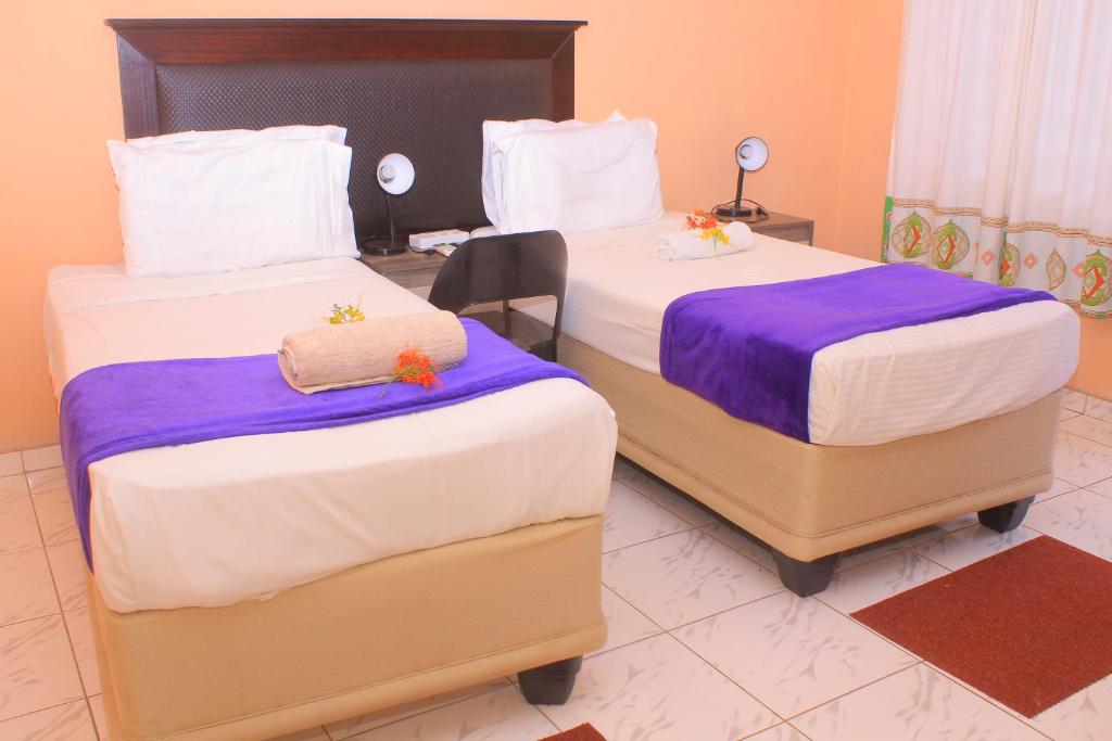 卡萨内Luma Guest House的客房内的两张床,配有紫色和白色床单