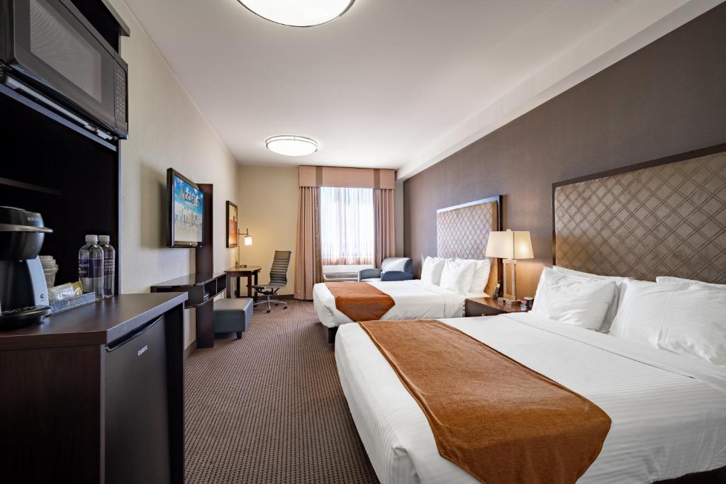 卡尔加里Acclaim Hotel by CLIQUE的酒店客房配有两张床和一张书桌