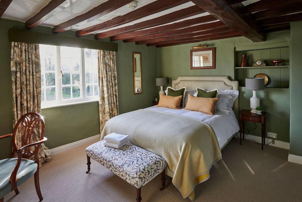 Colston BassettMartin Arms的绿色卧室配有一张大床和一把椅子