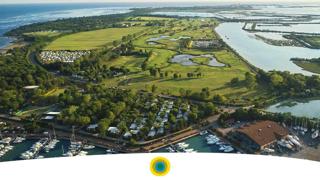 格拉多Resort Tenuta Primero的享有毗邻河流的高尔夫球场的空中景致