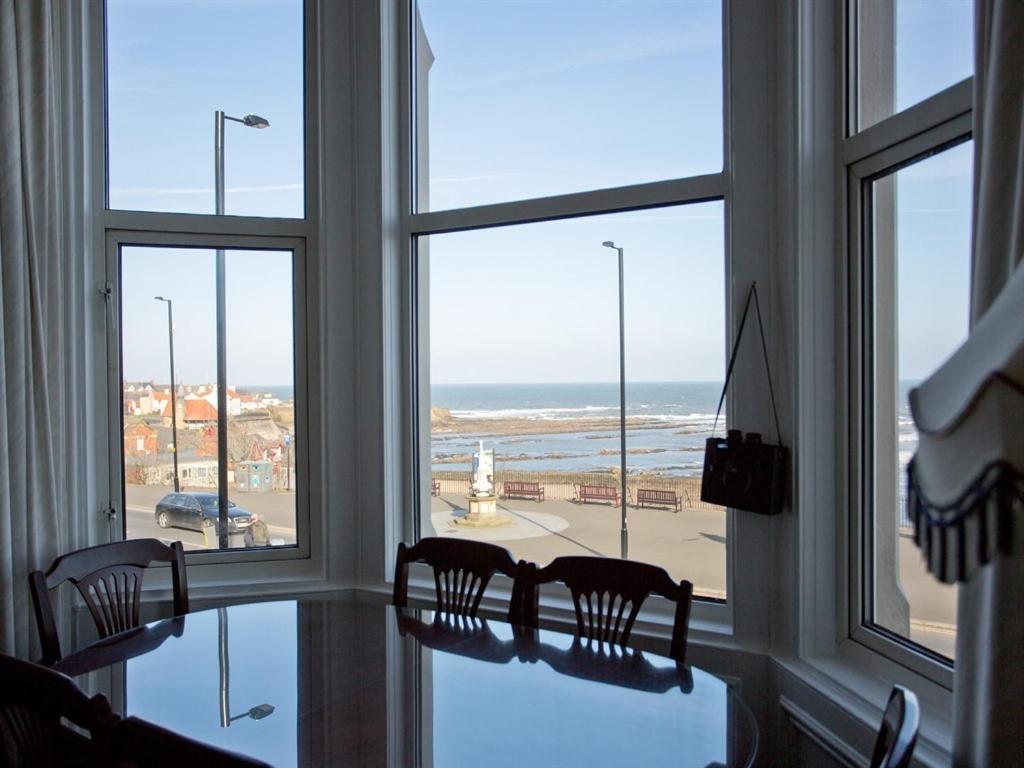 北希尔兹Seafront Apartments的配有桌椅的客房,俯瞰着大海