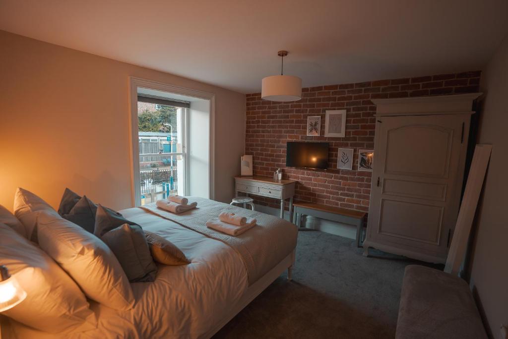 Whaley BridgeThe Jodrell Luxury Suites的一间卧室设有一张带砖墙的大床