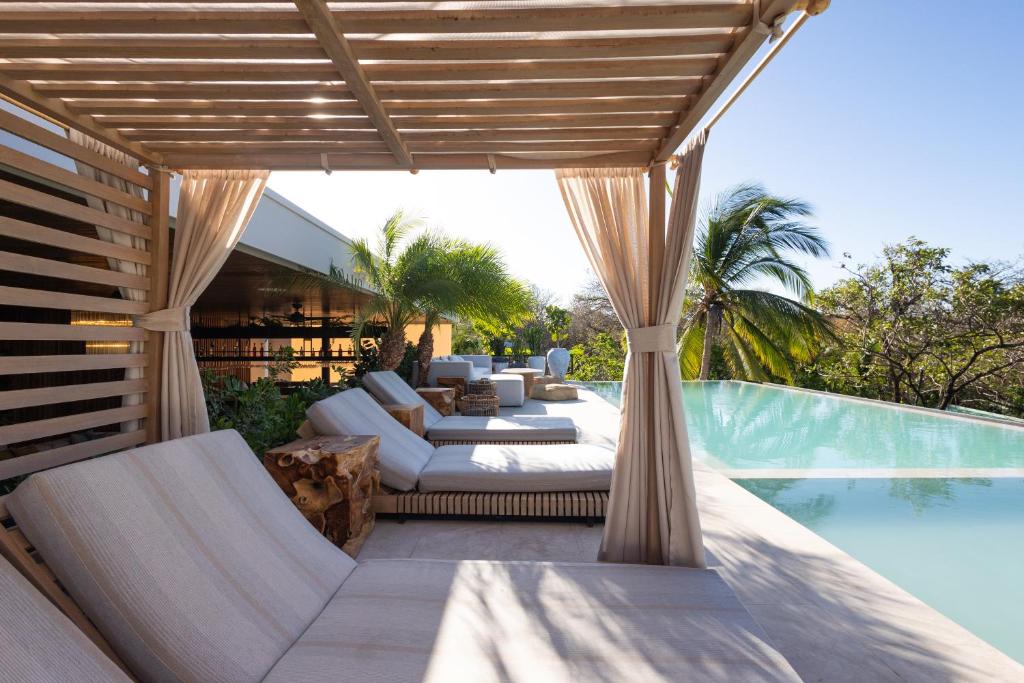 诺萨拉Silvestre Nosara Hotel & Residences的游泳池旁的户外庭院配有沙发和椅子