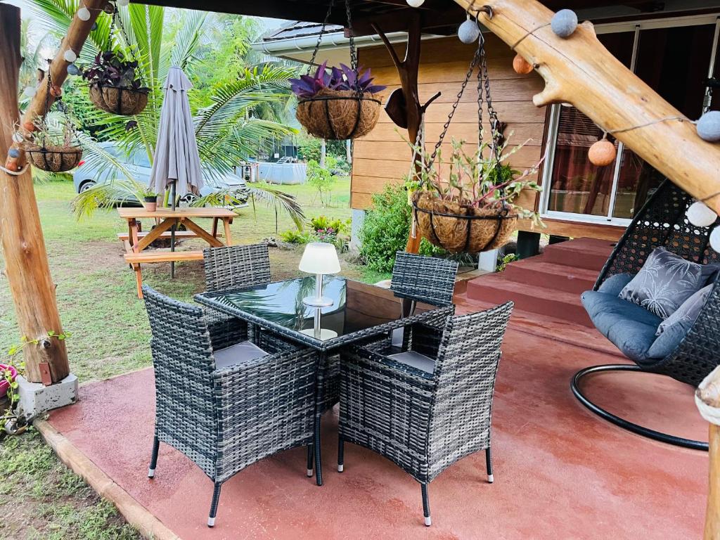 莫雷阿Bungalow KURA的一个带玻璃桌、椅子和遮阳伞的庭院