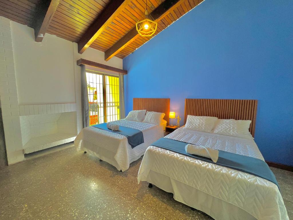 危地马拉Hotel Citadin Z10的一间卧室设有两张床和蓝色的墙壁