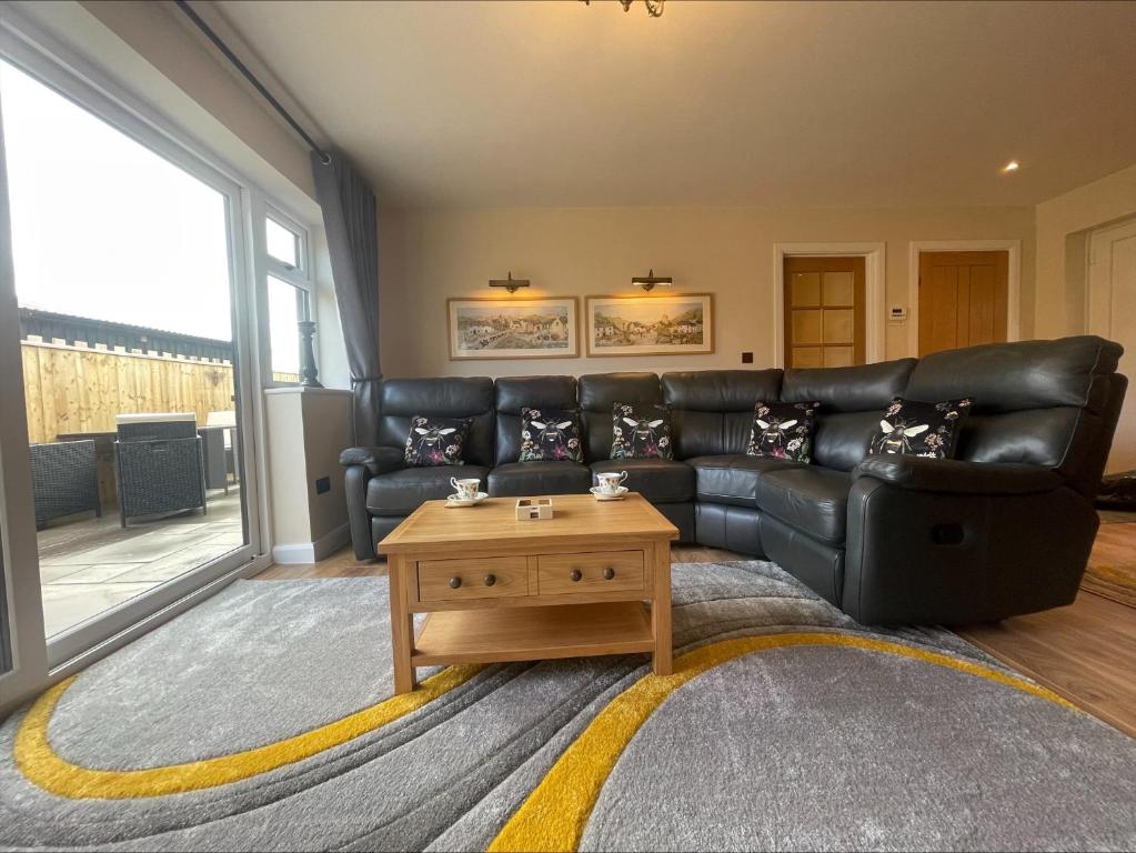 佩伦波斯Bumblebee Barn, Luxury contemporary holiday home的客厅配有黑色真皮沙发和咖啡桌