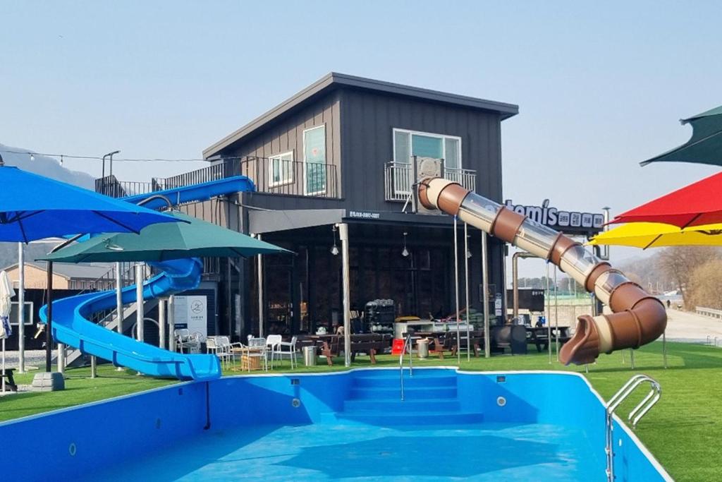 抱川市Pocheon Artemis Glamping的一个带水滑梯和遮阳伞的游乐场